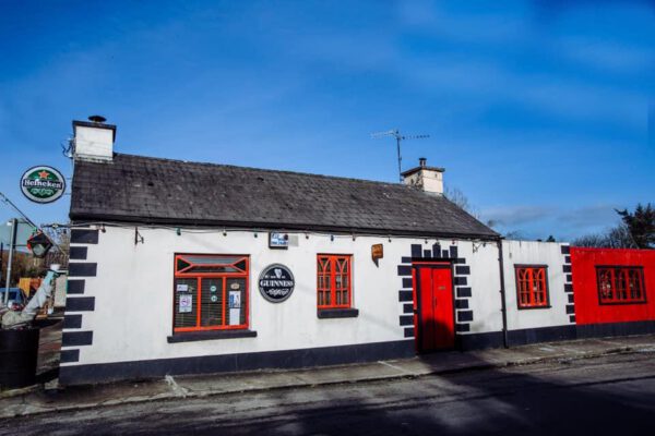 The whitewashed exterior of The Shanty Bar with its red door under a blue sky