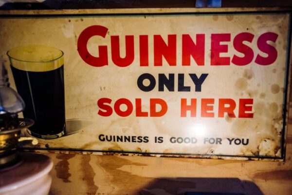 An old enamel Guinness sign beside a pint on the counter