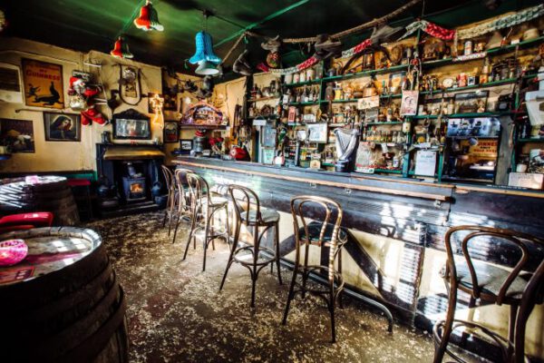 Bar stools along the counter with barrels and framed pictures on the walls