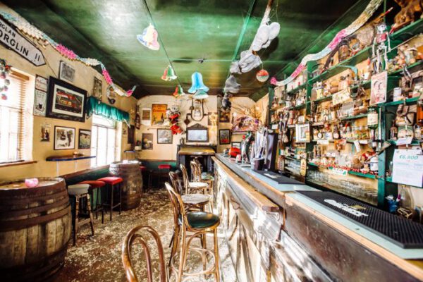 A long view down the bar under a green ceiling hung with pictures