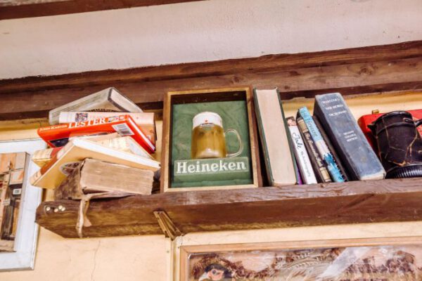 A shelf of old books beside a framed brewery mirror